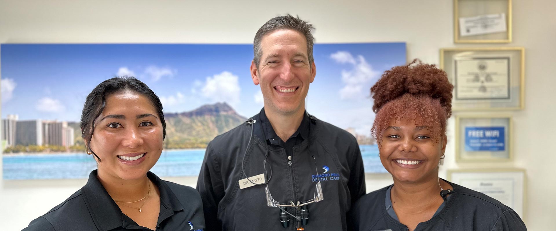 The image shows three individuals standing in front of a backdrop with a scenic view  they appear to be at an event, possibly related to tourism or hospitality, given their attire and the setting.