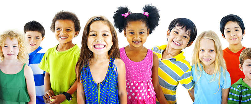 The image shows a group of children standing together in front of a plain background with various expressions on their faces.