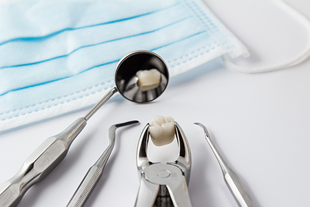 The image shows a collection of dental tools including a toothbrush with toothpaste on its bristles placed next to a set of dental instruments, all laid out against a blue cloth background, suggesting a dental care or dental hygiene setting.