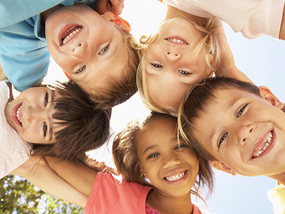 A group of children, possibly siblings, smiling at the camera with their arms around each other.